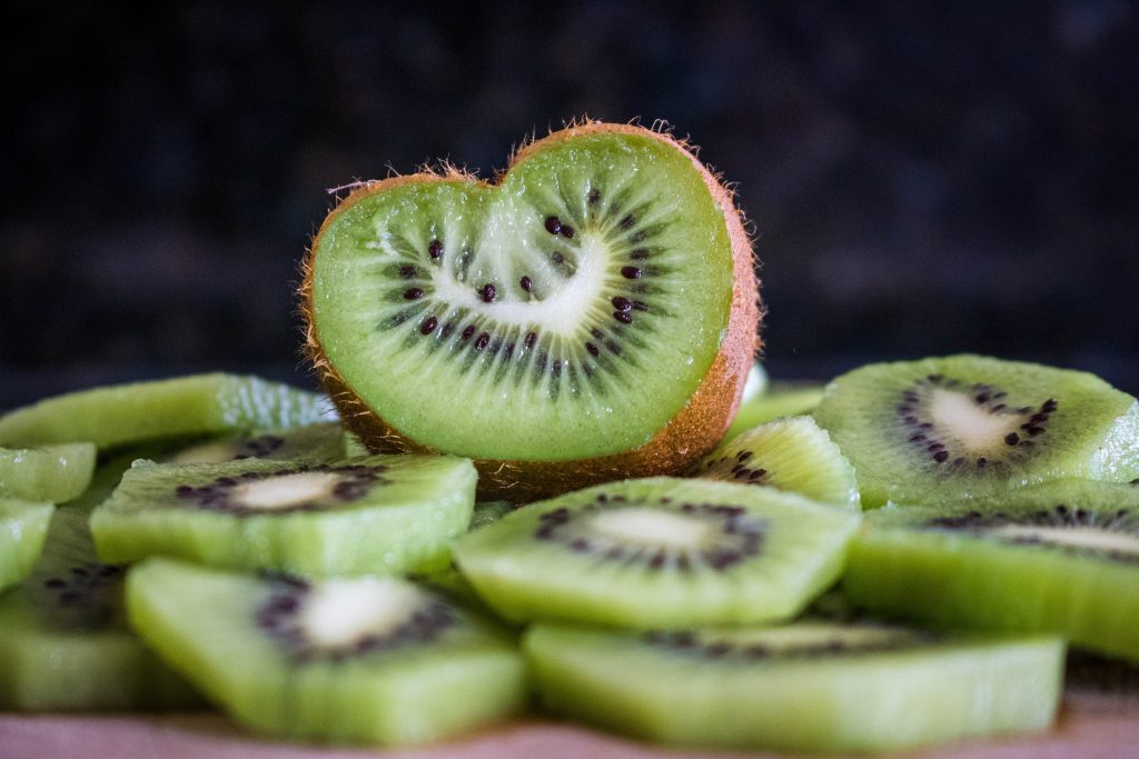 Photo of kiwi slices peeled and a half of a kiwi shaped in a heart.